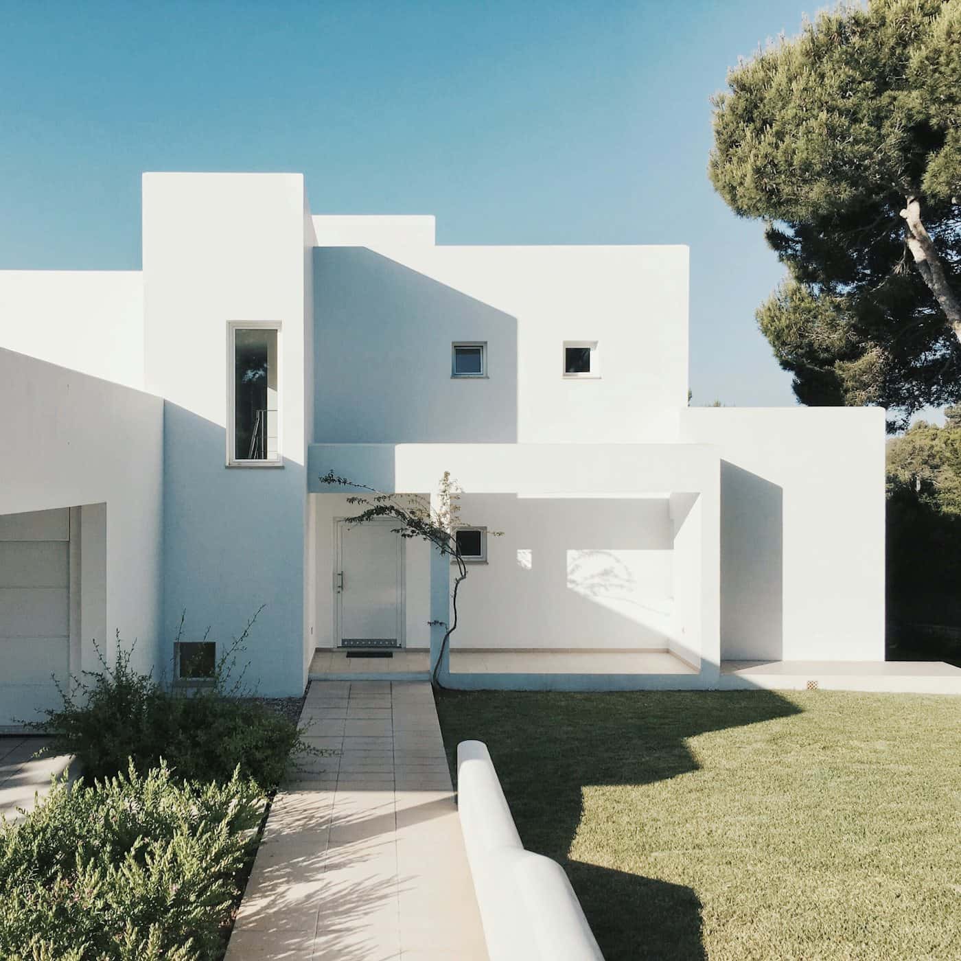 Casa blanca de volúmenes puros con jardín